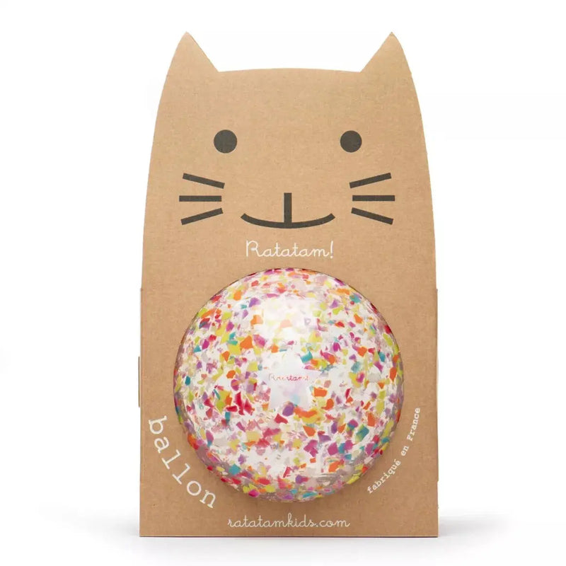 Une balle de confettis colorée est emballée dans un support en carton en forme de visage de chat, avec des moustaches et des oreilles dessinées. L'emballage indique marque Ratatam ! 