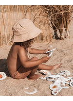 un enfant qui manipule le puzzle de bain mrs ertha assis sur le sable
